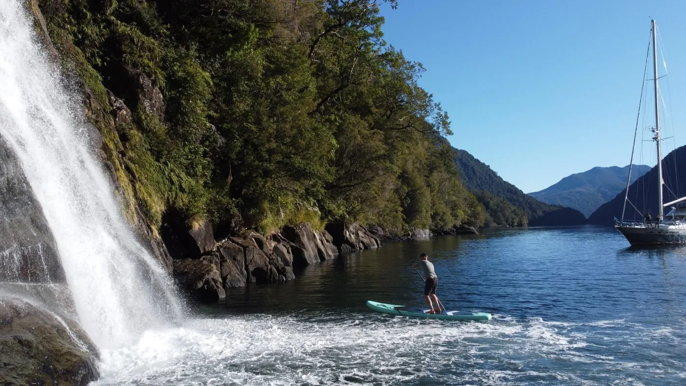 Velero frente a una cascada en una ruta por fiordos patagónicos